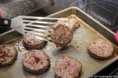 hamburger patties being cooked on a grill with a spatula in it's hand