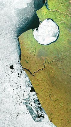 an aerial view of water and land in the middle of winter, taken from space