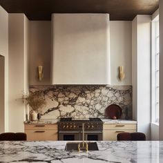 a kitchen with marble counter tops and an island in the middle, surrounded by brown chairs