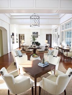 a living room filled with white furniture and lots of windows on top of the walls