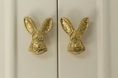 two golden rabbit head hooks on a white door