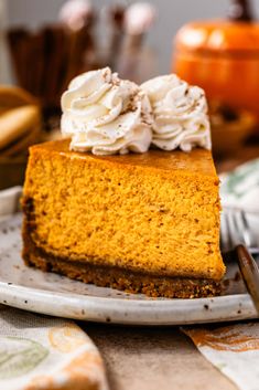 a slice of pumpkin cheesecake on a plate with whipped cream and fork next to it