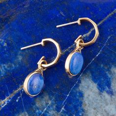 Elevate your look with these luxe Nova Lapis and Bronze Earrings! Hand-crafted with genuine Lapis and bronze and finished by hand, this exquisite set will sparkle and shine wherever you go! The Lapis stone hangs 1.1" from a sterling post in a half-hoop, with a .08 oz weight and a blue stone set in a bronze bezel. Lapis Lazuli Description: Lapis Lazuli is renowned for its deep blue color, often speckled with golden pyrite inclusions that resemble stars in the night sky. This semi-precious stone h Luxury Blue Hoop Jewelry, Elegant Blue 14k Gold Hoop Earrings, Lapis Stone, Bronze Earrings, Green Jasper, Golden Earrings, Bronze Ring, Sparkle And Shine, Turquoise Howlite