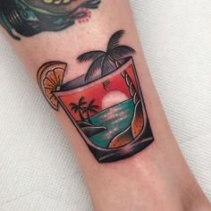 a tattoo on the leg of a person with a drink and palm trees in it