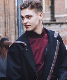 a young man is standing next to a pole