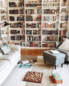 a living room filled with lots of furniture and bookshelves covered in shelves full of books