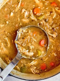 a ladle full of chicken soup with carrots and celery