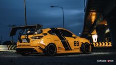 the yellow car is parked on the side of the road near a bridge at night