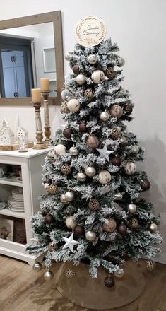 a decorated christmas tree in a living room with white and gold ornaments on the top