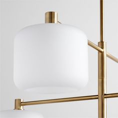 two white glass lamps hanging from a brass frame