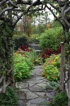 a stone path leads to a garden with flowers and trees in the backround