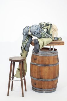 an old wooden barrel with a scarf on top and a stool next to it, in front of a white background