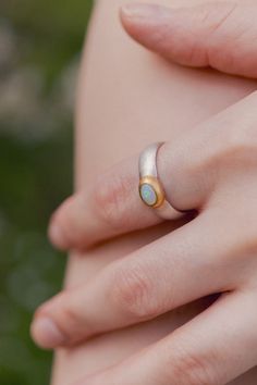 This elegant ring features a matte silver band adorned with a single opal stone, elegantly set in a gold bezel. The subtle contrast between the warm gold and the cool opal adds a touch of sophistication, making it a versatile piece suitable for any occasion. Handcrafted with attention to detail, this ring is perfect for those who appreciate understated elegance with a hint of color. Sterling silver  Gold vermeil  Opal  To properly care for your silver jewellery, there are a few important steps y Oval Opal Ring, Stocking Fillers For Her, Forever Jewelry, Jewelry Ring Box, Silver Jewelry Handmade, Opal Stone, Elegant Ring, Understated Elegance, Opal Ring