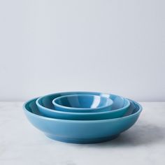 three blue bowls are stacked on top of each other in front of a white wall