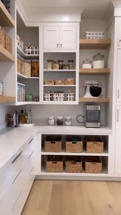 a kitchen with white cabinets and lots of baskets on the counter top in front of it