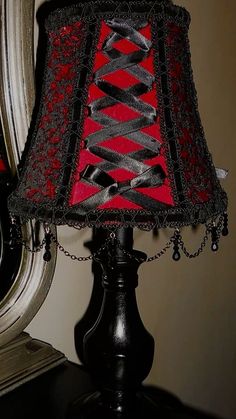 a red and black lamp on a table next to a mirror with a chain around it