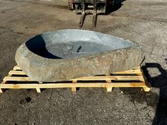 a large stone bowl sitting on top of wooden pallets