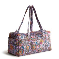 a multicolored bag with handles and straps on the handle is sitting upright against a white background