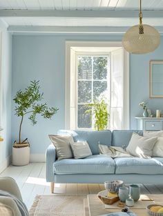 a living room with blue walls and white flooring is pictured in this image, the couch has many pillows on it