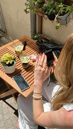 a woman sitting at a table with her cell phone in front of her and flowers on the side