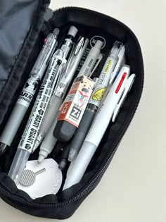 a black case filled with lots of pens and writing utensils on top of a white table