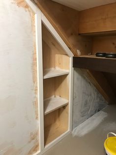 an unfinished room with shelves and buckets on the floor