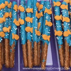 blue and gold fish pretzel sticks are in plastic containers with white sprinkles