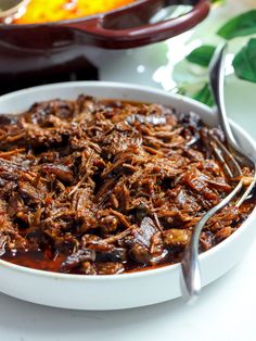 a white bowl filled with meat and sauce