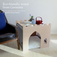 a dog house made out of wood with a cat bed on the floor next to it