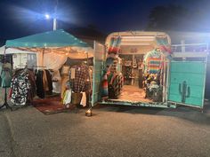 an old camper trailer with clothes on display in the open door at night time