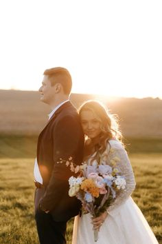 a bride and groom standing in a field at sunset with the sun shining on them