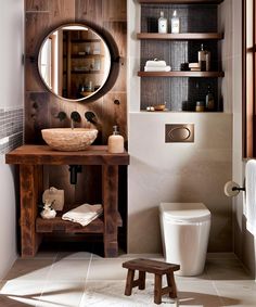 a bathroom with a toilet, sink and mirror in it's corner area next to a wooden shelf