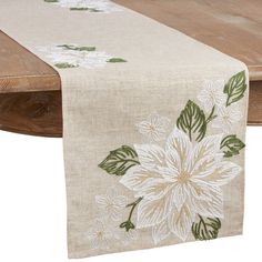 a table runner with white flowers and green leaves