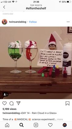 the elf on the table is holding a sign and two wine glasses are sitting next to each other