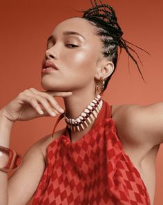 a woman in a red top is posing with her hand on her chin