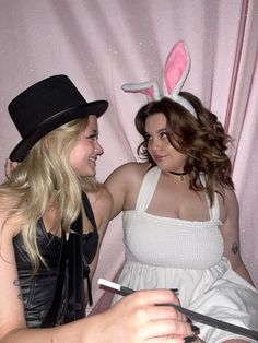 two women in bunny ears are sitting next to each other and one is holding scissors