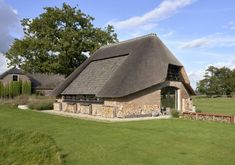 an old thatched roof house in the middle of a field