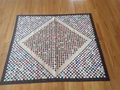 a quilted area rug on the floor with wooden floors