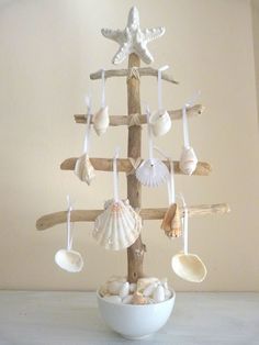 a white bowl filled with seashells on top of a wooden pole in front of a wall