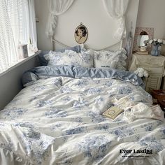 a bed with blue and white comforters in a bedroom next to a window,