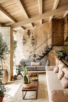 a living room filled with furniture and potted plants next to a stone wall covered in wood