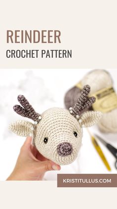 a crocheted reindeer is being held up by someone's hand with scissors and yarn