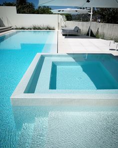 an empty swimming pool with blue water and white furniture in the backround area