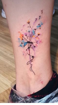 a woman's leg with a dandelion tattoo on her left side ribcage