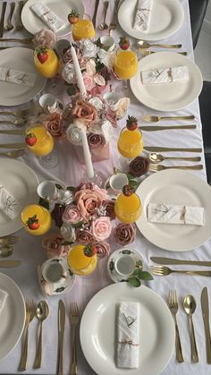 the table is set with white plates, silverware and pink flowers in vases