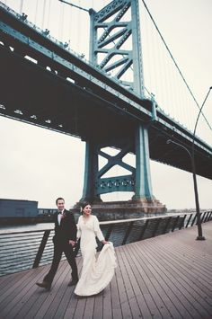 a bride and groom are walking under the bridge