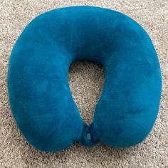 a blue neck pillow laying on the floor in front of a white carpeted area