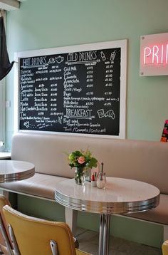 a table with two chairs and a chalkboard on the wall in a restaurant setting