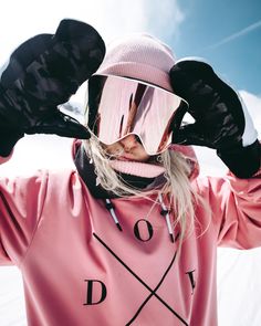 a woman wearing ski goggles and a pink sweater