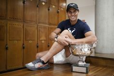 a man sitting on the floor next to a trophy